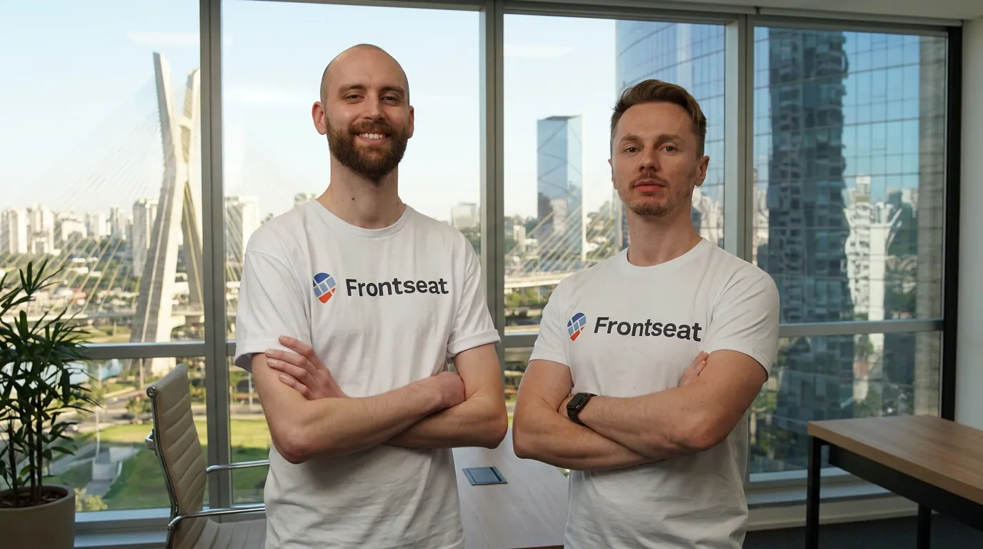 Os dois fundadores da Frontseat, de camiseta da marca, num escritório com vista para São Paulo